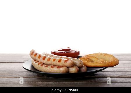 Plate with sausages, sauce and pretzel on table against white background. Oktoberfest celebration Stock Photo