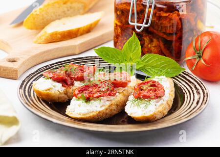 Sandwiches with sun-dried tomatoes, cheese and dill in a plate on the table Stock Photo