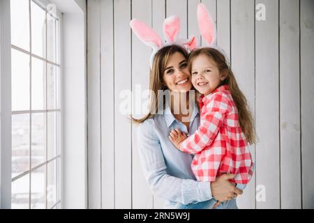 Young woman bunny ears holding daughter arms Stock Photo