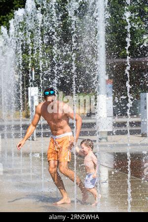 (150704) -- GENEVA, July 4, 2015 -- A father and his child run through fountains on Nations Square in Geneva, Switzerland, July 4, 2015. World Meteorological Organisation (WMO) announced Friday that the heatwave affecting parts of Western, Central and Eastern Europe since June 27 will continue unabated over the coming days. ) SWITZERLAND-GENEVA-WMO-EUROPE-HOT WAVES XuxJinquan PUBLICATIONxNOTxINxCHN   150704 Geneva July 4 2015 a Father and His Child Run Through Fountains ON Nations Square in Geneva Switzerland July 4 2015 World Meteorological Organization WMO announced Friday Thatcher The Heat Stock Photo