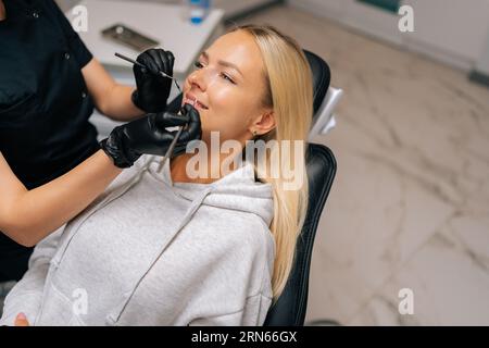 Closeup top view of smiling young woman having treatment in dentistry clinic. Cropped shot of unrecognizable female dentist in gloves examining Stock Photo
