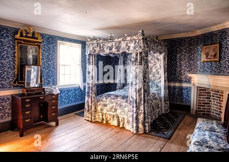 Mount Vernon Bedroom Alexandria VA // MOUNT VERNON, Alexandria, VA — The blue wallpaper room showcases period-style decor in one of the bedrooms at Mount Vernon, the historic estate of George Washington, first President of the United States. This meticulously preserved bedroom reflects the aesthetic and furnishing styles typical of late 18th-century upper-class American homes. Mount Vernon, situated along the Potomac River, served as Washington's home from 1754 until his death in 1799. The estate has been maintained by the Mount Vernon Ladies' Association since 1858 and stands as one of Americ Stock Photo