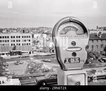 1970s AN EXPIRED PARKING METER WITH VIEW OF URBAN INDUSTRIAL AREA - s20760 HAR001 HARS OLD FASHIONED Stock Photo