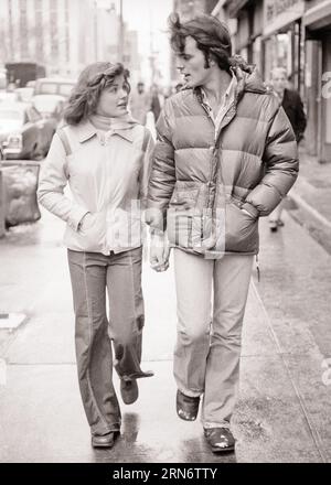 1970s YOUNG COUPLE TALKING WALKING DOWN CITY STREET HOLDING HANDS MAN WEARING QUILTED DOWN JACKET BOTH WEARING JEANS - s20667 HAR001 HARS JACKET NOSTALGIC PAIR ROMANCE URBAN JEANS RELATIONSHIP OLD TIME NOSTALGIA OLD FASHION 1 JUVENILE YOUNG ADULT COTTON LIFESTYLE FEMALES COPY SPACE FRIENDSHIP FULL-LENGTH LADIES PERSONS MALES DENIM B&W DATING HOLDING HANDS ATTRACTION COURTSHIP TEENAGED WINDY POSSIBILITY BLUE JEANS INFORMAL JUVENILES SOCIAL ACTIVITY TOGETHERNESS TWILL YOUNG ADULT MAN YOUNG ADULT WOMAN YOUNGSTER BLACK AND WHITE CASUAL CAUCASIAN ETHNICITY COURTING HAR001 OLD FASHIONED QUILTED Stock Photo