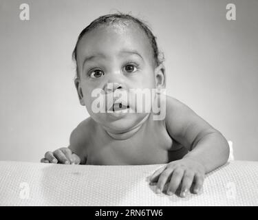 1960s CUTE AFRICAN-AMERICAN BABY BOY CHUBBY CHEEKS FACIAL EXPRESSION OF WONDER AWE LOOKING AT CAMERA HAND REACHING FORWARD - n2314 HAR001 HARS CHUBBY EXPRESSIONS AMAZED B&W EYE CONTACT WONDER BUG-EYED AWE HAPPINESS HEAD AND SHOULDERS DISCOVERY AFRICAN-AMERICANS AFRICAN-AMERICAN CHEEKS BLACK ETHNICITY CONCEPTUAL AMAZE CURIOUS JOWLS BABY BOY WIDE-EYED GROWTH JUVENILES BLACK AND WHITE HAR001 OLD FASHIONED QUIZZICAL AFRICAN AMERICANS Stock Photo