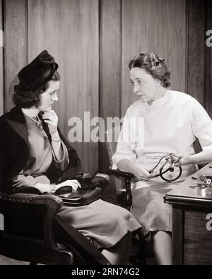 1940s FEMALE DOCTOR IN OFFICE HAVING A SERIOUS CONSULTATION CONVERSATION WITH A WOMAN PATIENT - m1824 HAR001 HARS STUDIO SHOT COPY SPACE HALF-LENGTH LADIES PENSIVE PERSONS THOUGHTFUL CARING RISK NERVOUS CONFIDENCE EXPRESSIONS TROUBLED MIDDLE-AGED B&W CONCERNED SADNESS HEALTHCARE OCCUPATION MIDDLE-AGED WOMAN PROVIDER PROVIDERS ANXIOUS DISCOVERY PRACTITIONERS HEALING KNOWLEDGE PHYSICIANS HEALTH CARE HESITANT OCCUPATIONS HEALER APPREHENSIVE PHYSICIAN PRACTITIONER UNEASY MID-ADULT MID-ADULT WOMAN PROFESSIONALS YOUNG ADULT WOMAN BLACK AND WHITE CAUCASIAN ETHNICITY HAR001 OLD FASHIONED Stock Photo