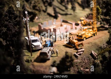 Choo Choo Barn Miniature Construction Workers Diorama Strasburg | STRASBURG, Pennsylvania, United States — Miniature construction workers, a utility truck, blue tractor, bulldozer, and tower crane populate a hillside building site inside the Choo Choo Barn's G-scale layout. The Choo Choo Barn, opened in 1961 in the heart of Pennsylvania's Amish country, uses over 150 animated actions to bring its 1,700-square-foot (158 sq m) model world to life. Stock Photo