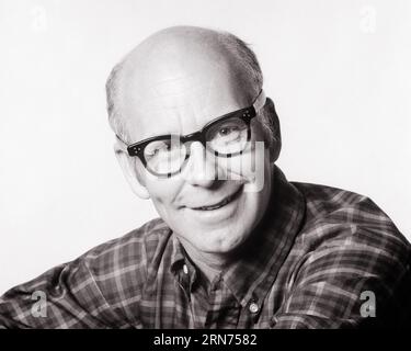 1960s 1970s SMILING BALDING MIDDLE-AGED MAN WITH CLEFT IN HIS CHIN WEARING A CASUAL PLAID SHIRT EYEGLASSES AND LOOKING AT CAMERA - p7934 HAR001 HARS HEAD AND SHOULDERS CHEERFUL HIS BALDING AND SMILES FRIENDLY JOYFUL INTERESTED BLACK AND WHITE CASUAL CAUCASIAN ETHNICITY HAR001 OLD FASHIONED Stock Photo