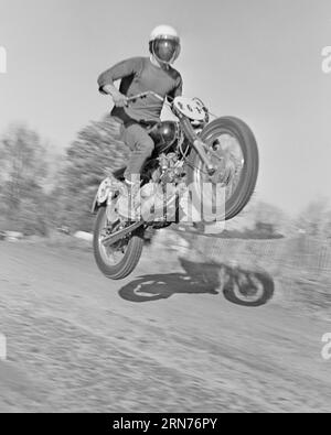 1960s ANONYMOUS MAN RIDING A MOTORCYCLE IN A MOTOCROSS COMPETITION AIRBORNE OVER THE STOP OF A MOUND WEARING A HELMET - m8391 HAR001 HARS INTEREST EXCITEMENT HOBBIES KNOWLEDGE POWERFUL PASTIME MOUND PLEASURE AIRBORNE ANONYMOUS MOTORCYCLES MOTOCROSS RELAXATION AMATEUR BIKER BLACK AND WHITE CAUCASIAN ETHNICITY ENJOYMENT HAR001 OLD FASHIONED Stock Photo
