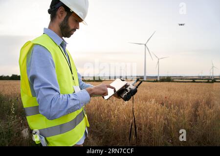 European engineer focused on using drone to inspect wind farm. People and technology in workplace. Stock Photo