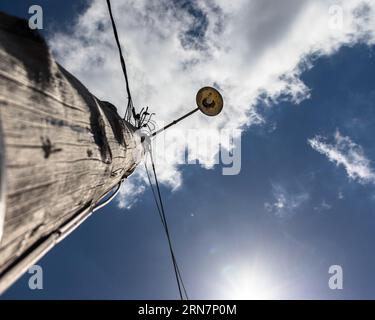 Low angle view of an old wooden electricity pole. Blue clear sky with few clouds. Stock Photo
