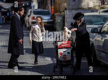 (150922) -- JERUSALEM, Sept. 21, 2015 -- An ultra-Orthodox Jewish boy helps a Jewish girl to put a white chicken back to her stroller in Mea Shearim, Jerusalem, on Sept. 21, 2015, ready to hold the traditional kaparot ceremony home ahead of Yom Kippur, the Jewish Day of Atonement and the holiest day of the Jewish calendar, which falls from sunset of Sept. 21 to sunset of Sept. 23 this year. It is customary to perform the kaparot (symbolic atonement ) rite in preparation for Yom Kippur. The rite consists of taking a chicken and waving it over one s head three times while reciting the appropriat Stock Photo