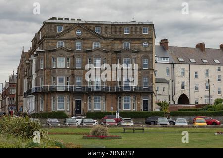 Whitby, North Yorkshire, UK - July 5th 2023 - Historic old building in Whitby with cars parked in front and a manicured garden with benches Stock Photo