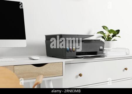 Modern printer with paper on chest of drawers indoors Stock Photo