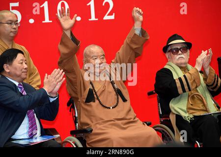 (151012) -- NANJING, Oct. 12, 2015 -- Master Hsing Yun (C), founder of the influential Fo Guang Shan Monastery in southeast China s Taiwan, waves while sitting next to Chinese painting artist Li Chimao (R) during the launching ceremony of an academy built for Chinese art research in a campus of Nanjing University in Nanjing, capital of east China s Jiangsu Province, Oct. 12, 2015. The academy building is named after Hsing Yun for his devotion in 2010 to the project. Located inside the building, the Li Chimao Art Museum was officially opened on Monday. ) (yxb) CHINA-NANJING-NEW COLLEGE BUILDING Stock Photo