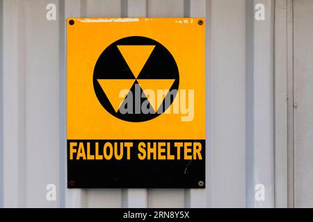 Black nuclear symbol drawn on a yellow placard with written in "Fallout shelter". Stock Photo