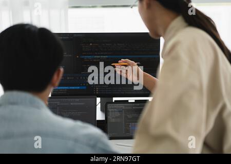 Two developer programmer discussing to checking code on monitor about programming to developing web. Stock Photo