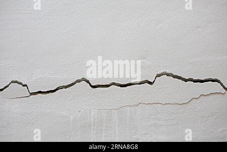 cracks on cement wall The concept of the image tells of danger or damage. Stock Photo