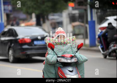 (160119) -- DONGYANG, Jan. 19, 2016 -- A woman wrapped in thick winter dress rides in Dongyang, east China s Zhejiang Province, Jan. 19, 2016. Most parts of China will experience a rapid drop in temperatures along with snow and rain in the coming days as a strong cold front is on the way, and will disrupt travel for the upcoming Spring Festival, which falls on Feb. 8 this year. The National Meteorological Center said temperatures will drop sharply in northwestern, northern and northeastern China, with temperatures in some areas down by up to 14 degrees Celsius. )(wjq) CHINA-COLD WAVE (CN) Baox Stock Photo