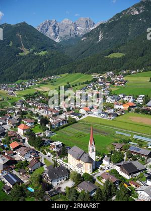 AERIAL VIEW. The Church of St. Pankratius in Telfes. In the distance, the Schlicker Seespitze (2804m) in the Kalkkögel Massif. Tyrol, Austria. Stock Photo
