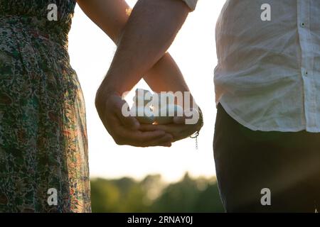 Conceptual image of gender reveal against homophobia: Couple waiting for the birth of their daughter with baby white shoes in hand Stock Photo