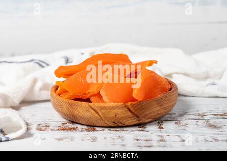 Natural dried mango slices in bowl on wooden background. Fruit snack for a health diet and alternative desert Stock Photo