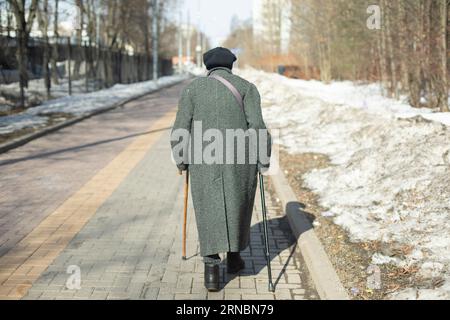 A blind elderly man with a disability, walks through a lush park ...