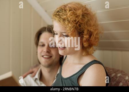 Couple reading book together at home during weekend Stock Photo
