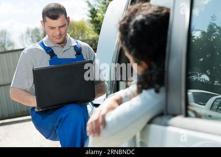 male mechanic using laptop for examining car engine Stock Photo