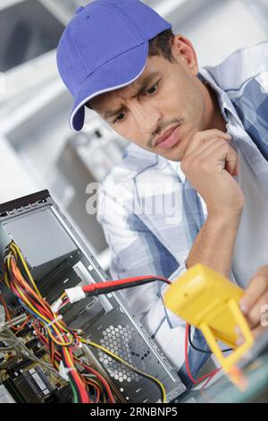 confused computer technician using multimeter Stock Photo