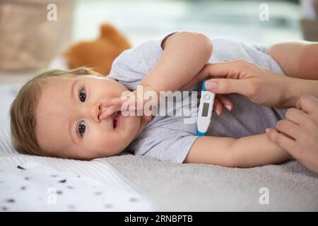 baby sick with measuring electric thermometer Stock Photo