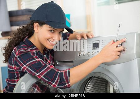 female plumber repairing washing machine Stock Photo