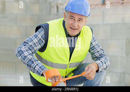 workman using adhesive tape outdoors Stock Photo