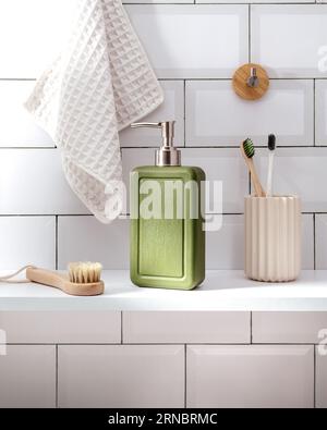 Dispenser of liquid soap and brush on wooden table in bathroom Stock Photo