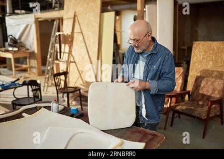 Portrait of experienced senior artisan working on furniture refurbishing in workshop, copy space Stock Photo