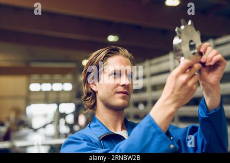 Young technician checking machine part in workshop Stock Photo