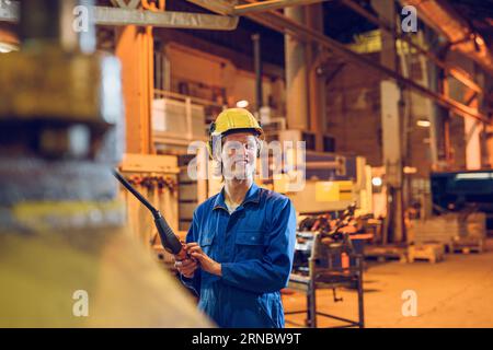 Smiling man working on factory with machine control panel Stock Photo