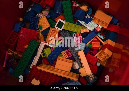A collection of lego toys random picked up on red container. Stock Photo