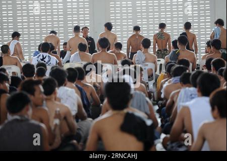 Thai men line up for physical examinations by an army doctor during a