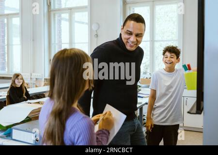 Happy male teacher having fun with students while teaching in classroom Stock Photo