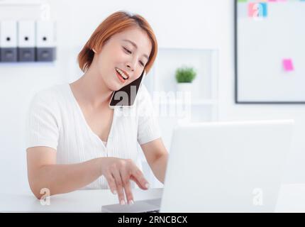 Happy woman using mobile phone and laptops for work. Stock Photo