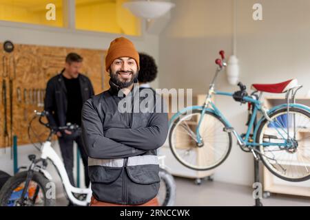 Portrait of happy male worker with arms crossed during cycle repairing workshop at recycling center Stock Photo