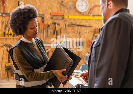 Female technician examining laptop while talking to customer at recycling center Stock Photo