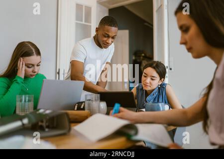 Young man studying with female friends at home Stock Photo