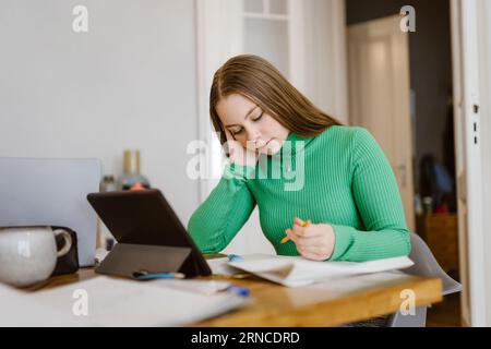 Bored young woman studying at table Stock Photo