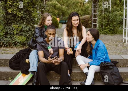 Young friends talking while sitting on steps Stock Photo