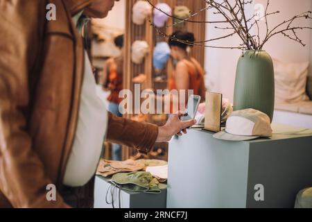 Midsection of senior man scanning QR code through smart phone at fashion clothing boutique Stock Photo