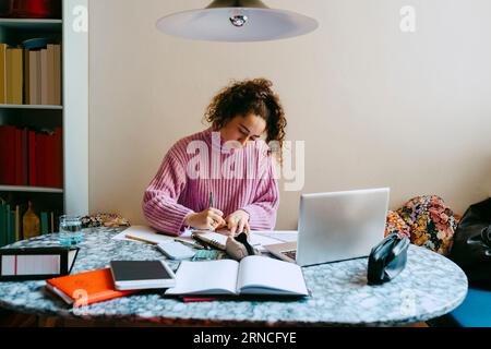 Young woman doing homework at table Stock Photo