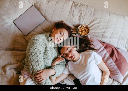Directly above shot of female friends lying on bed at home Stock Photo