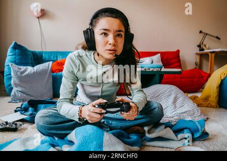 Woman wearing headset playing video game in living room at home Stock Photo